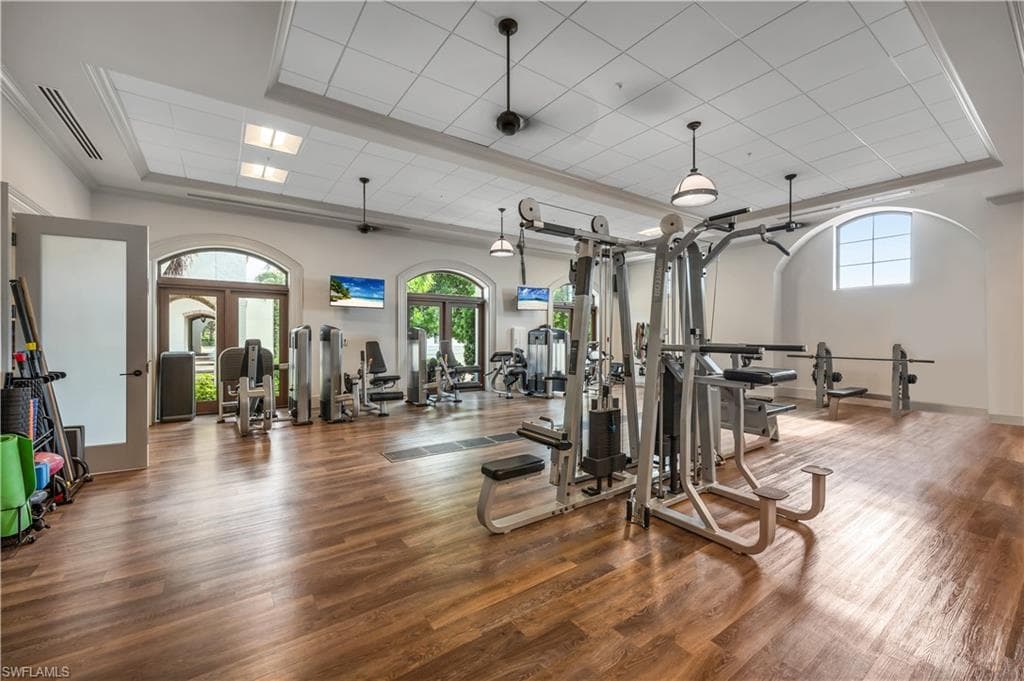 Spacious fitness center featuring wood-finish flooring, arched windows, and multiple exercise machines