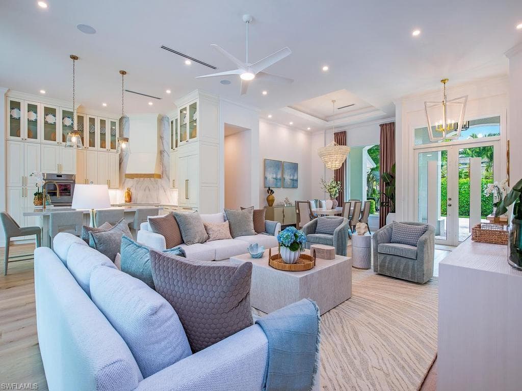 Open-concept living area featuring light wood-finish flooring, recessed lighting, and a tray ceiling