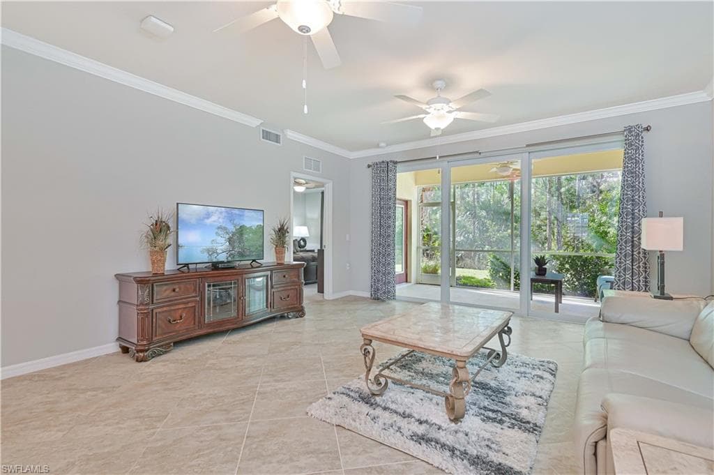 Spacious great room featuring volume ceilings, large-format tile flooring, and sliding glass doors that open to the screened lanai with peaceful preserve views.