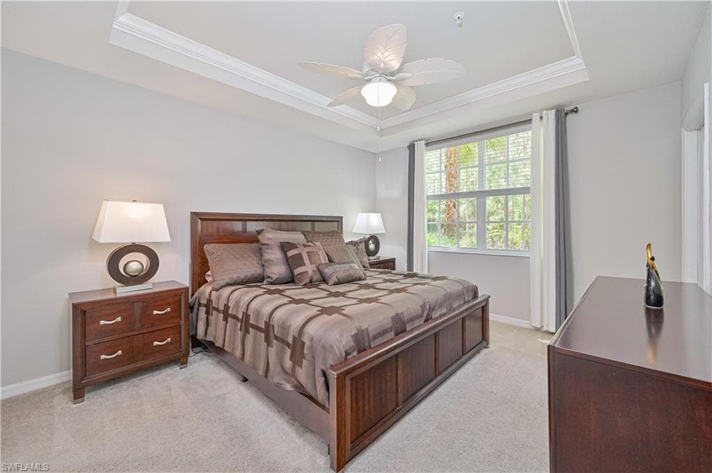 Spacious primary suite featuring a tray ceiling, large window with peaceful preserve views, plush carpeting, and a relaxing retreat-like atmosphere.
