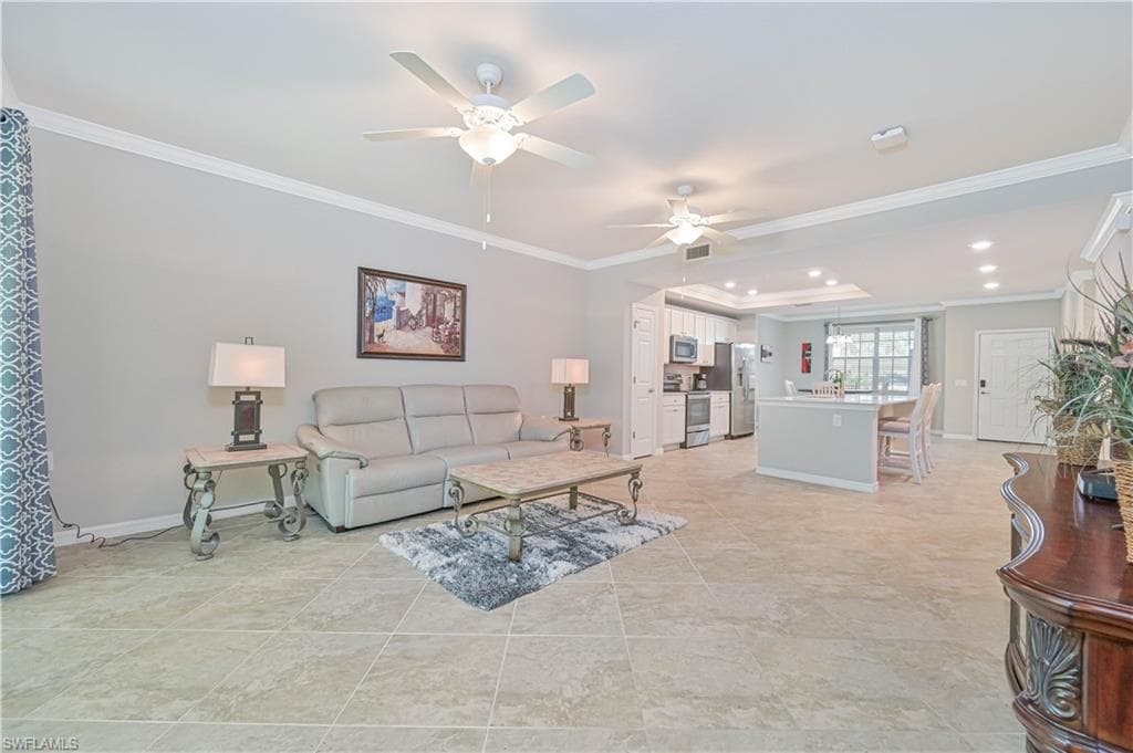 Expansive open-concept great room featuring volume ceilings, large-format tile flooring, and seamless flow to the kitchen, dining area, and screened lanai.
