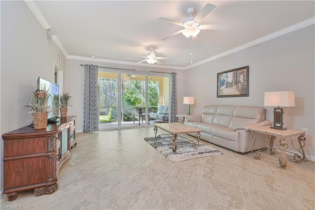Spacious great room featuring volume ceilings, tile flooring, abundant natural light, and seamless access to the screened lanai overlooking the preserve.