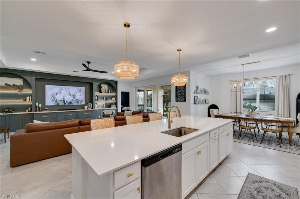 Expansive kitchen island featuring a stainless steel undermount sink, brass-finish faucet, and integrated dishwasher