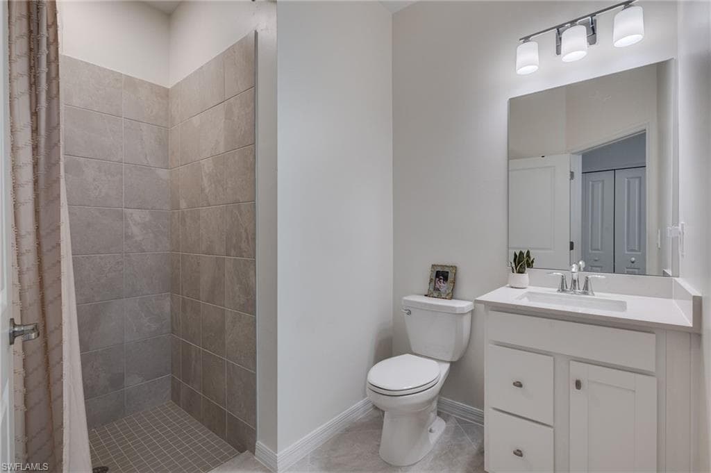 Bathroom featuring a tiled standing shower, white vanity with integrated sink, chrome faucet, and a large wall-mounted mirror
