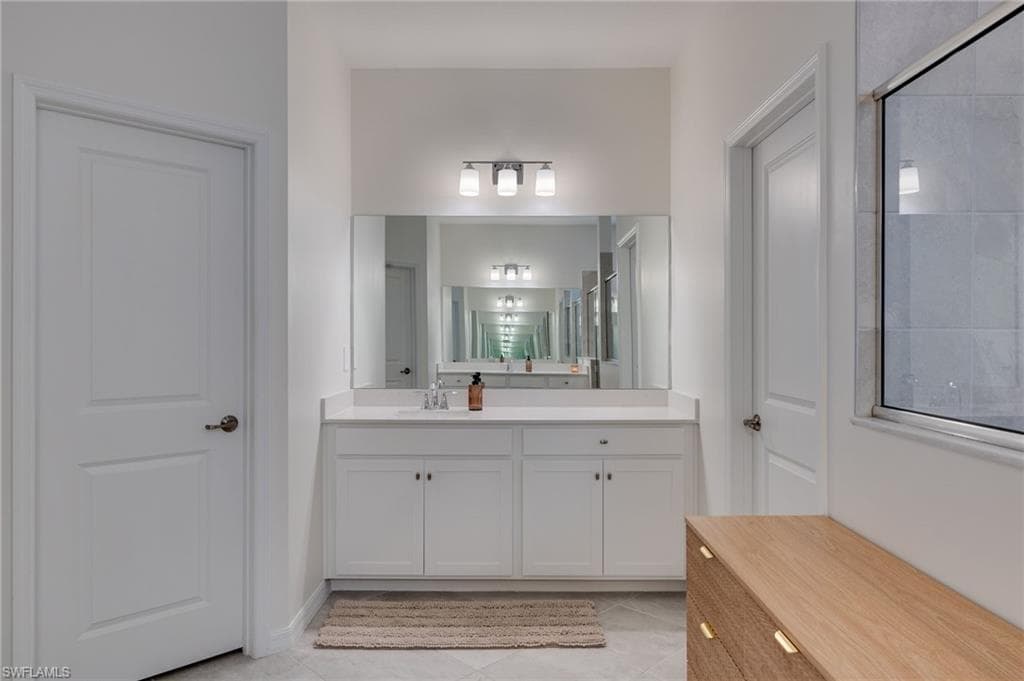 Dual-sink vanity with white cabinetry, light-toned countertop, and an expansive mirror