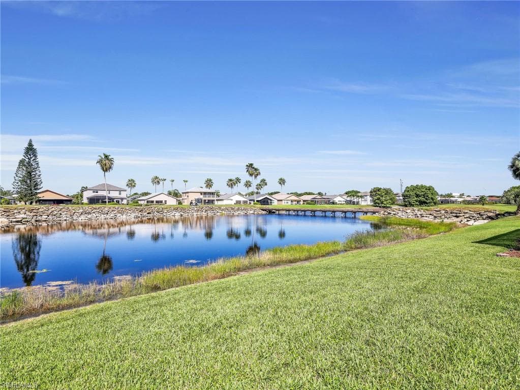 Expansive green lawn bordering a body of water with a rock-lined bank