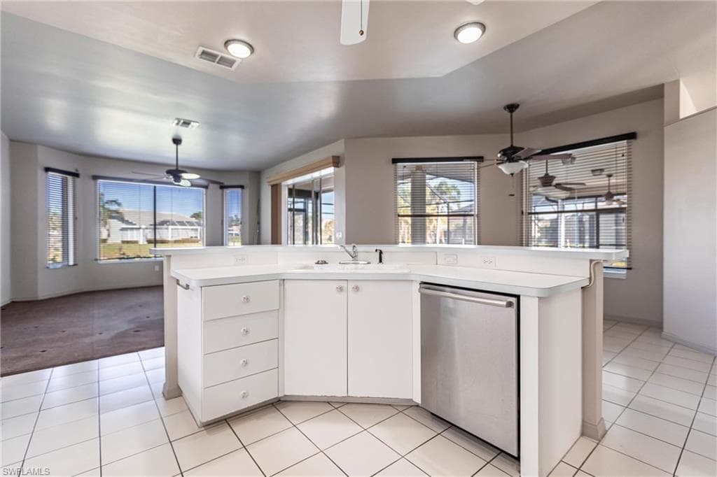 Kitchen with sink, dishwasher, ceiling fan, a kitchen island with sink, and white cabinets. Windowed eat-in dining area. Large pocket sliders lead to lanai. Views everywhere!