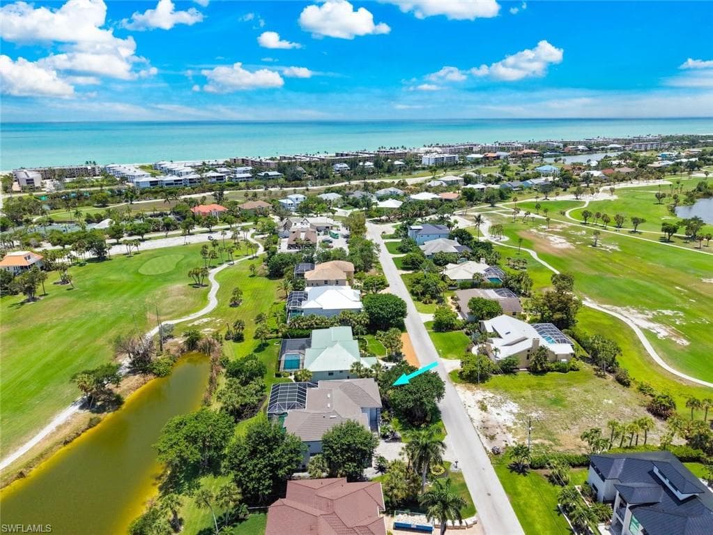 Aerial perspective featuring an extensive golf course, multiple residences, and a body of water