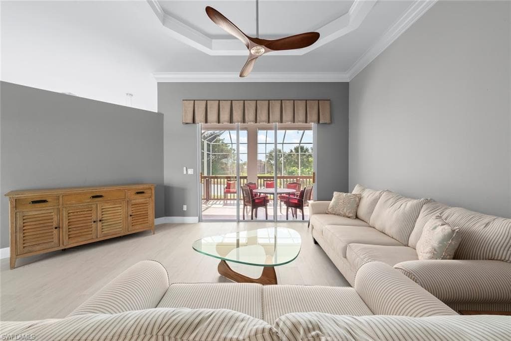 Living space featuring light wood-finish flooring and a tray ceiling with crown molding