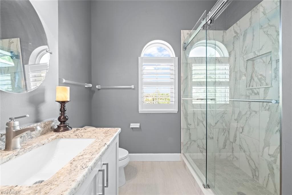 Bathroom featuring a glass-enclosed shower with marble-look wall tiles and a built-in niche
