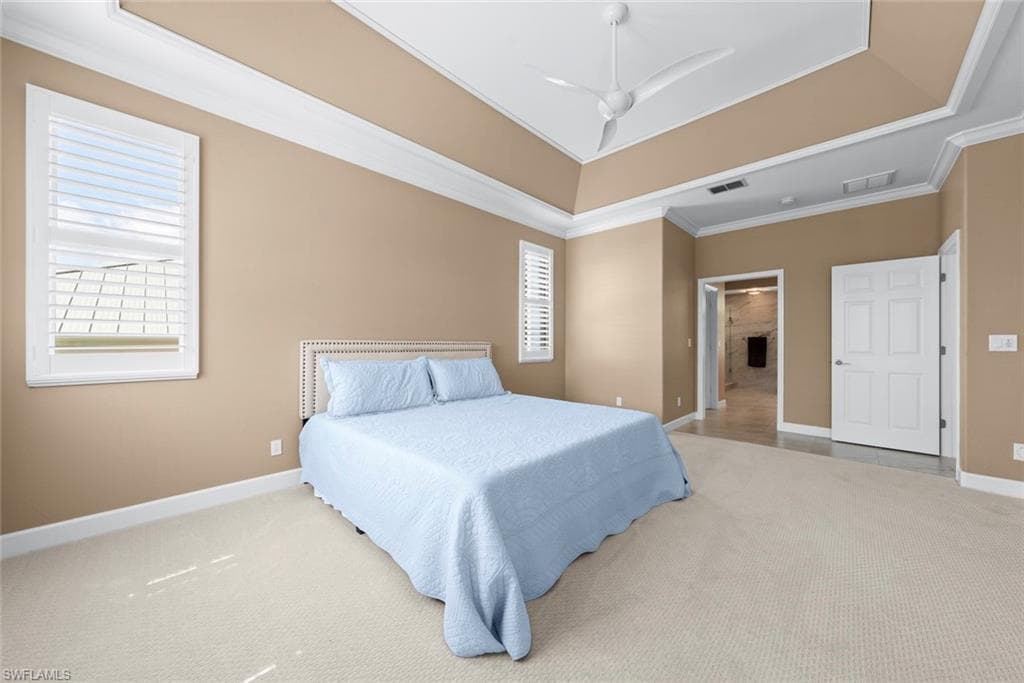 Spacious room with a tray ceiling, ceiling fan, and carpeted flooring