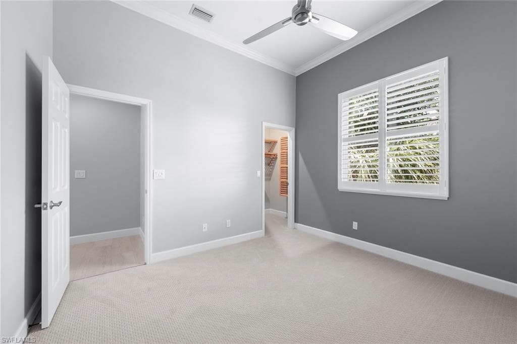 Spacious room featuring neutral carpeting, a modern ceiling fan, and a window with plantation shutters