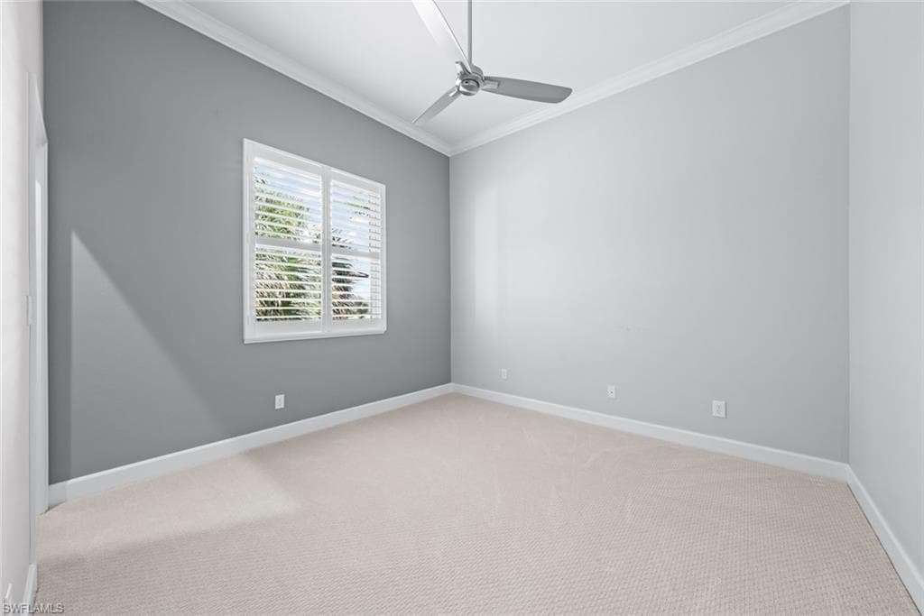 Room featuring a window with white louvered shutters, light gray painted walls, textured carpeting, white baseboards, and a ceiling fan