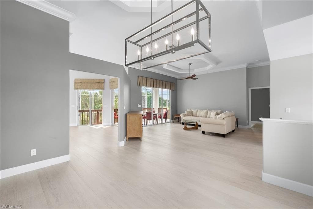 Expansive room featuring light wood-finish flooring, high vaulted ceilings, and a contemporary rectangular chandelier