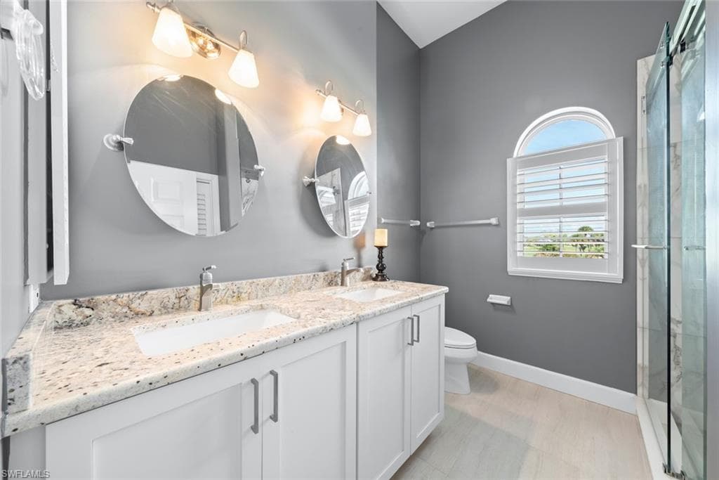 Bathroom featuring a dual vanity with granite countertops, white cabinetry, and undermount sinks