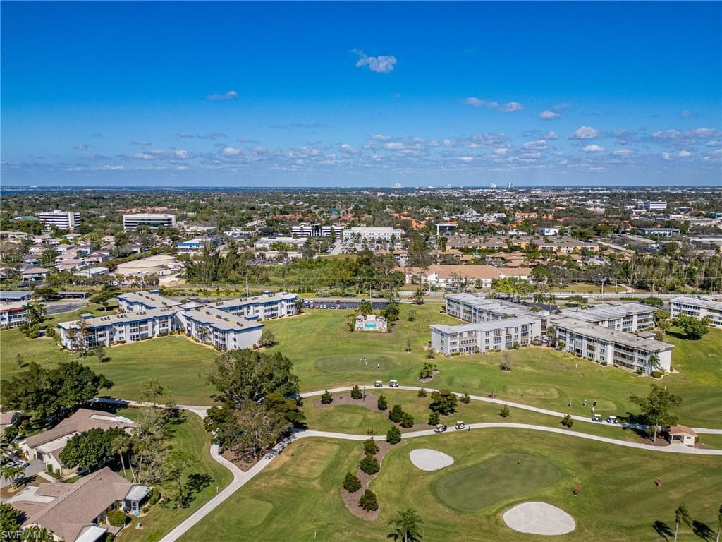 Expansive golf course property featuring multiple low-rise residential buildings, mature trees, manicured greens, and sand traps