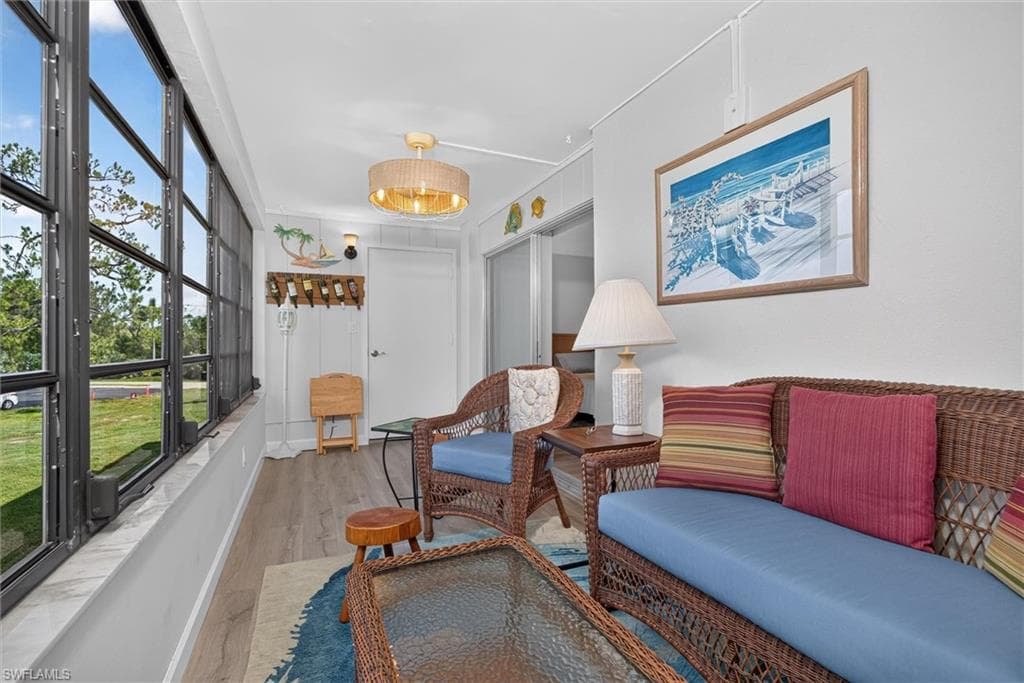 Lanai featuring a full wall of multi-pane windows, wood-finish flooring, a ceiling-mounted light fixture, and white wall finishes