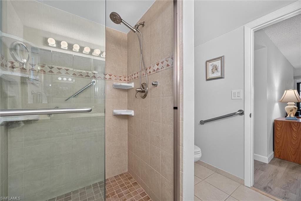 Master Bathroom Tiled shower enclosure featuring a glass door, handheld shower, and integrated shelving