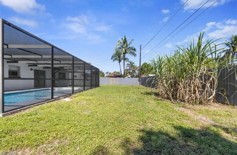 Expansive grassy yard with a screened-in swimming pool