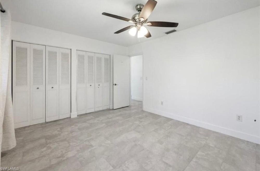 Spacious room featuring light-toned tile flooring, white walls, and a ceiling fan with integrated lighting