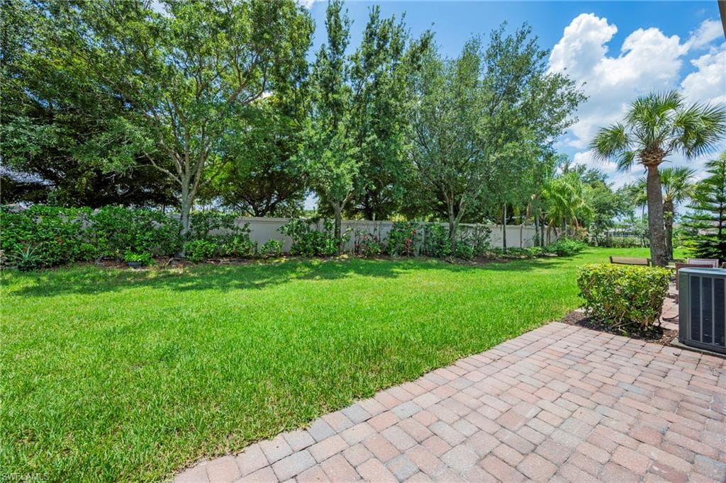 Expansive backyard with verdant lawn, mature trees, and a paver patio