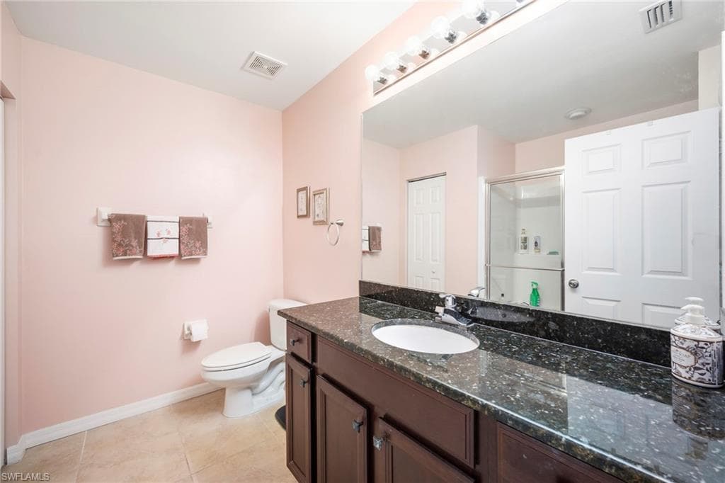 Bathroom featuring a dark-toned vanity with an integrated sink, a speckled countertop, and a large wall-mounted mirror