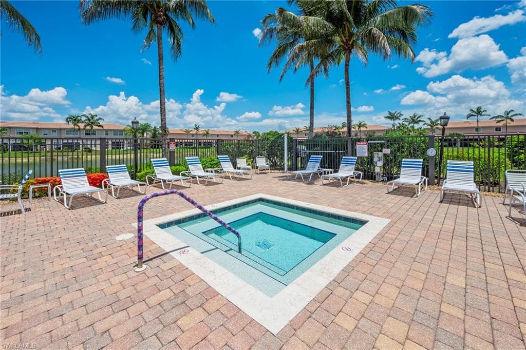 Outdoor hot tub featuring a paver patio surround, integrated steps, and a metal handrail