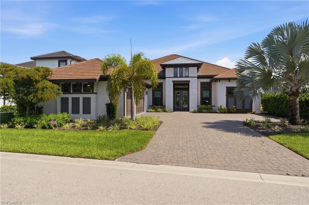 Contemporary stucco exterior with a tile roof and a paver driveway