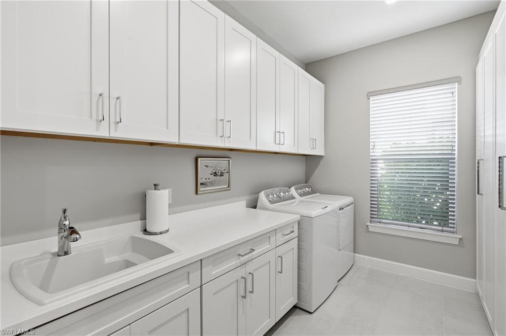 Utility room featuring extensive white shaker cabinetry, an integrated sink with a chrome faucet, a solid surface countertop, and light-toned flooring