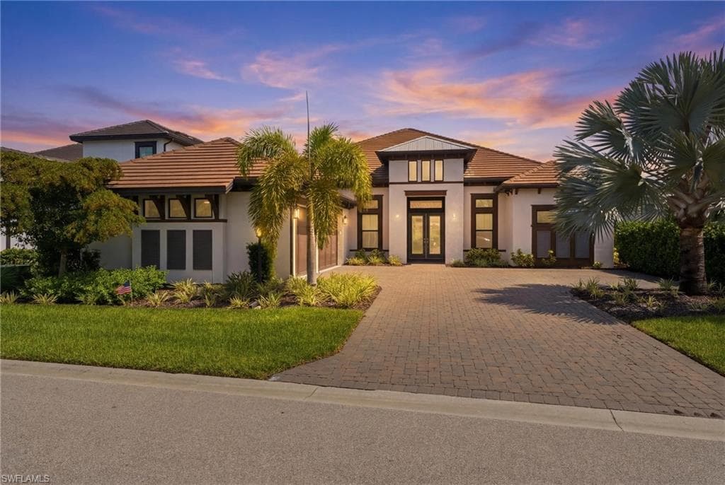 Contemporary architectural residence featuring a tile roof, paver driveway, and a two-car garage