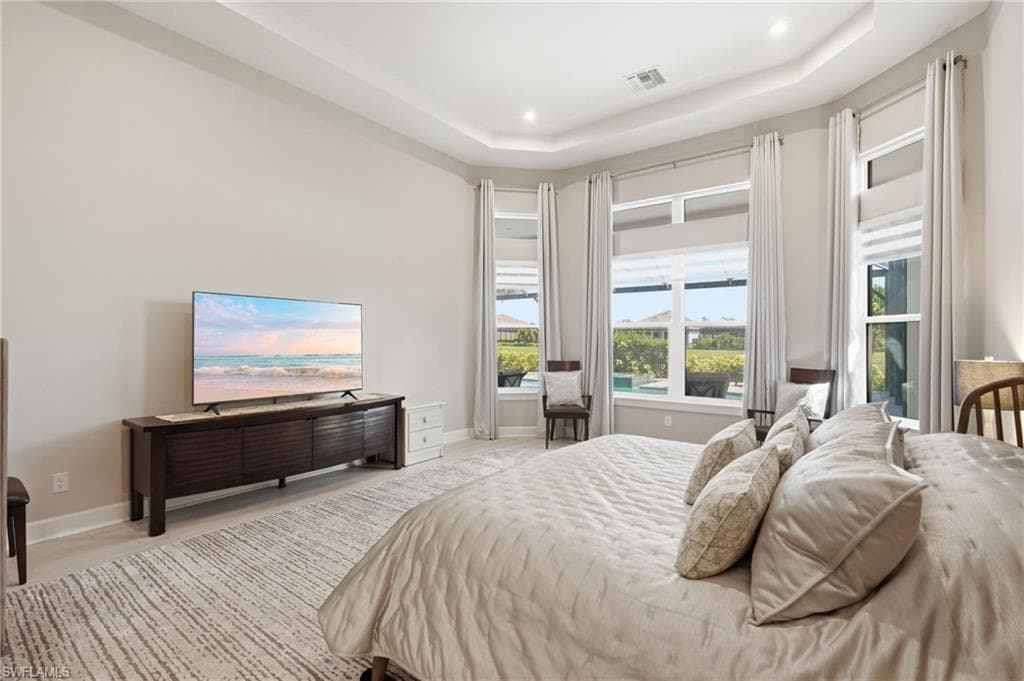 Spacious room featuring a tray ceiling with recessed lighting, light-toned walls, and large windows with privacy blinds