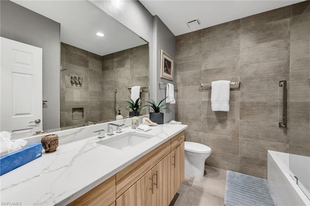 Spacious bathroom featuring a double vanity with a light wood-finish base and a white veined countertop, a large integrated mirror, and a walk-in shower with horizontal tilework