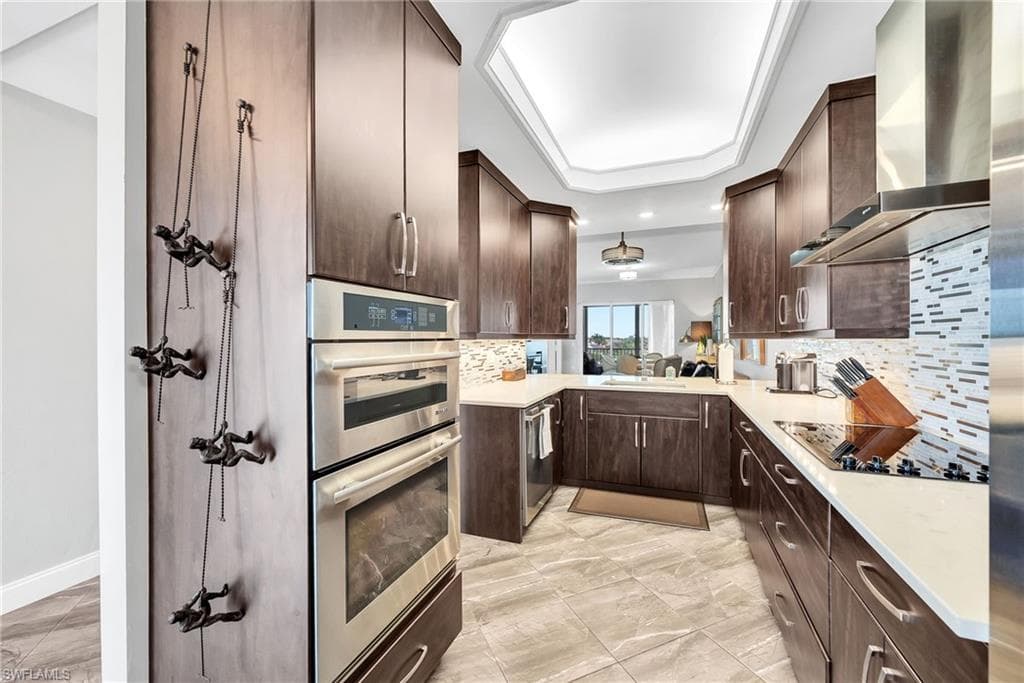 Gourmet kitchen featuring dark wood cabinetry, stainless steel double ovens, and a matching stainless steel range hood