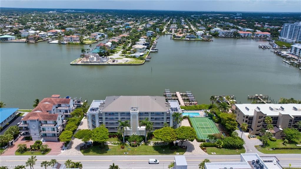 Waterfront community with multiple buildings, private boat docks, tennis court, and swimming pool