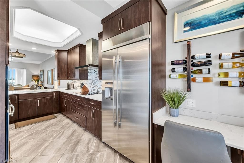 Gourmet kitchen featuring stainless steel appliances, dark wood-finish cabinetry, a tiled backsplash, and light-colored countertops