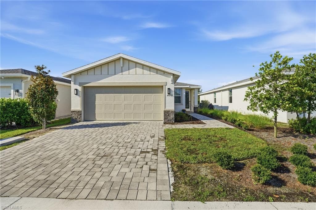 Contemporary single-story residence featuring a paver driveway, an attached garage, and stone accent siding