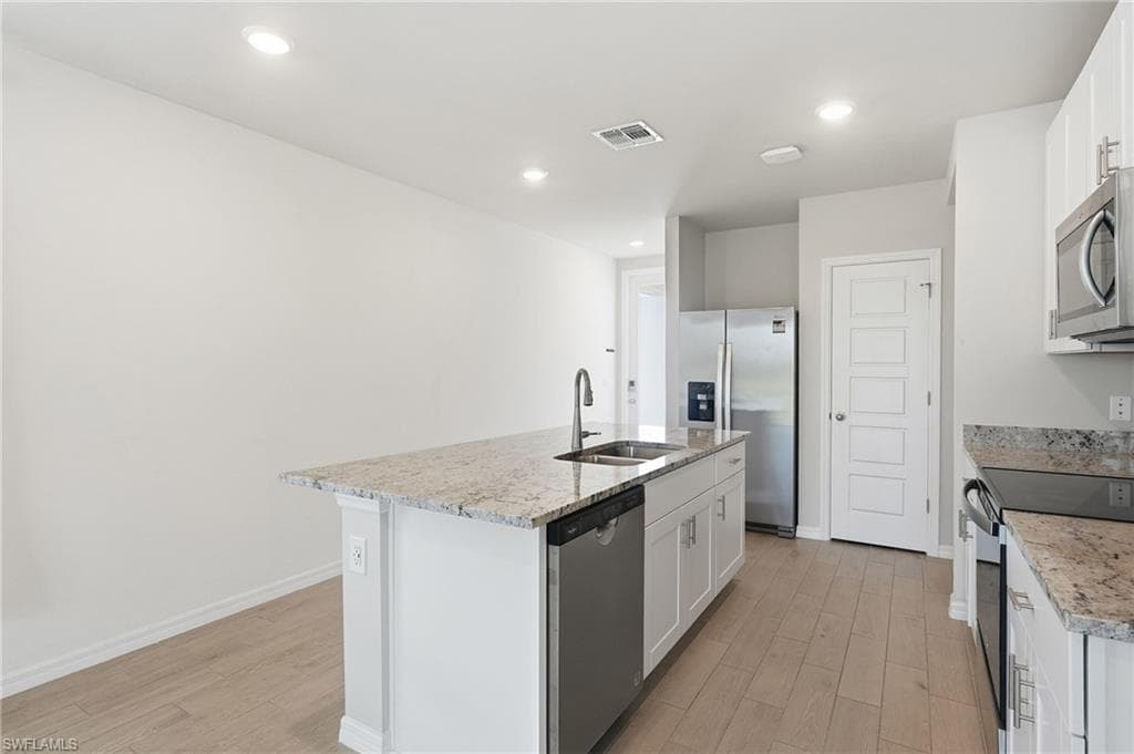 Modern kitchen featuring a central island with an undermount sink and stainless steel dishwasher