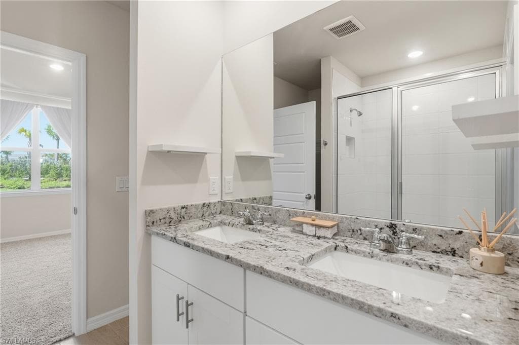Bathroom featuring a double vanity with stone countertops, integrated sinks, and chrome fixtures