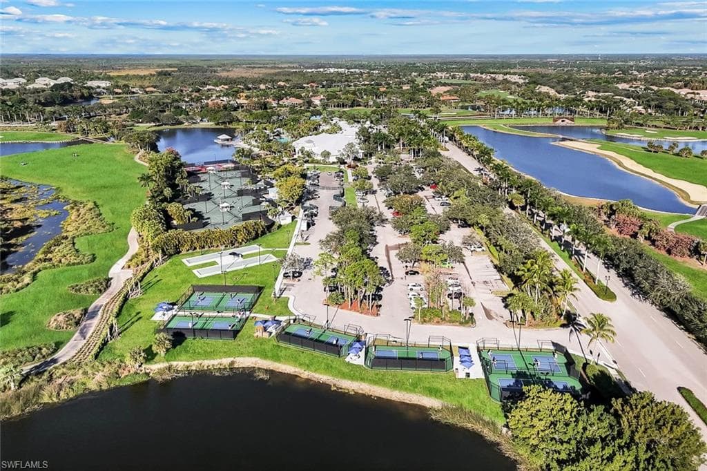 Aerial perspective showcasing multiple recreational courts, including tennis and pickleball, alongside a substantial parking area and mature landscaping