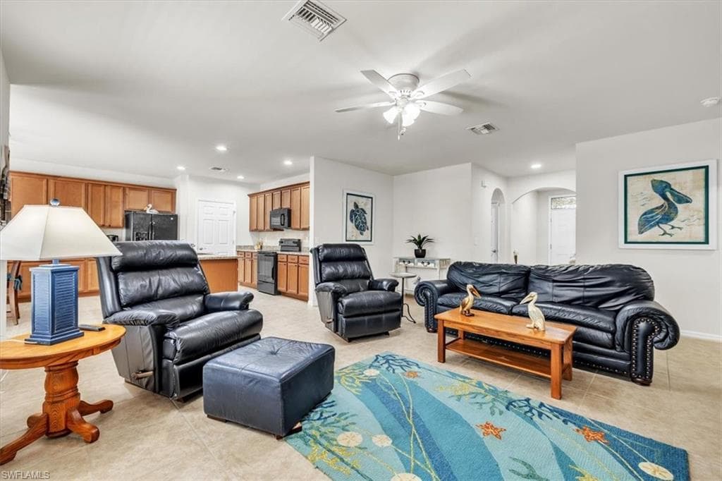 Open-concept floor plan with neutral, over-sized tile flooring and a ceiling fan