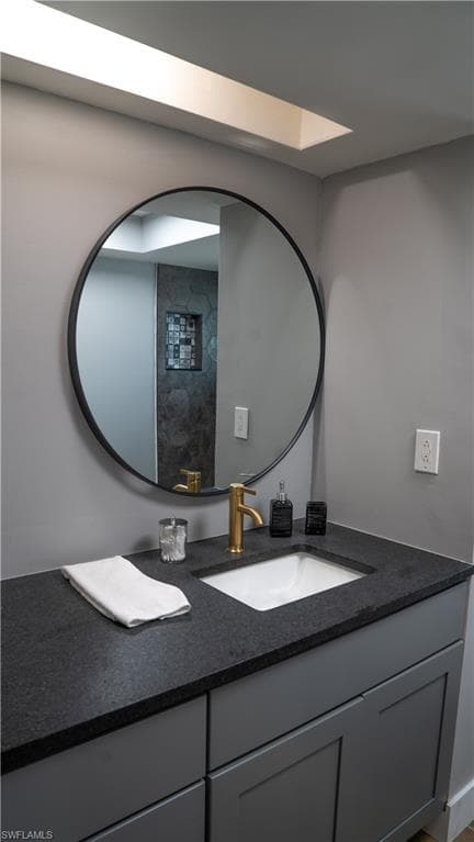 Modern vanity with a dark countertop, an undermount sink, and a gold-finish faucet