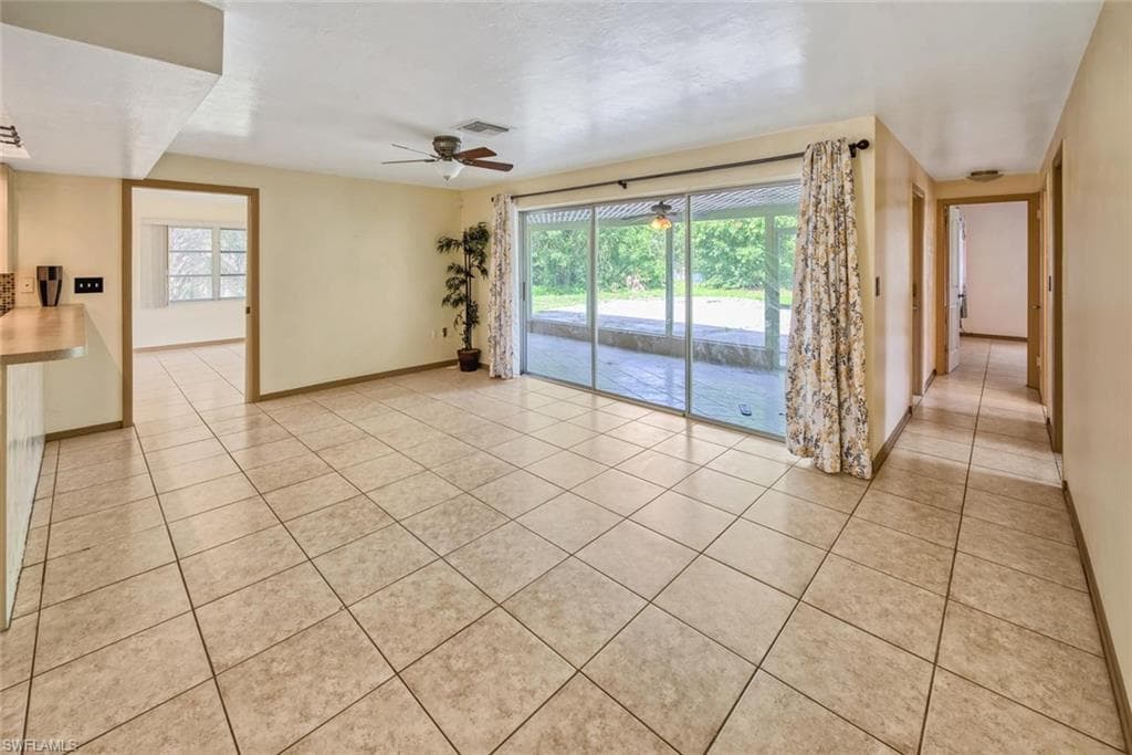 Empty room with light tile patterned floors and ceiling fan
