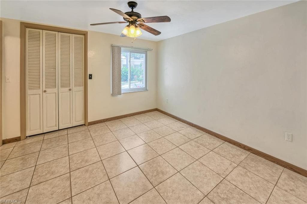 Unfurnished bedroom featuring a closet, ceiling fan, and light tile patterned flooring