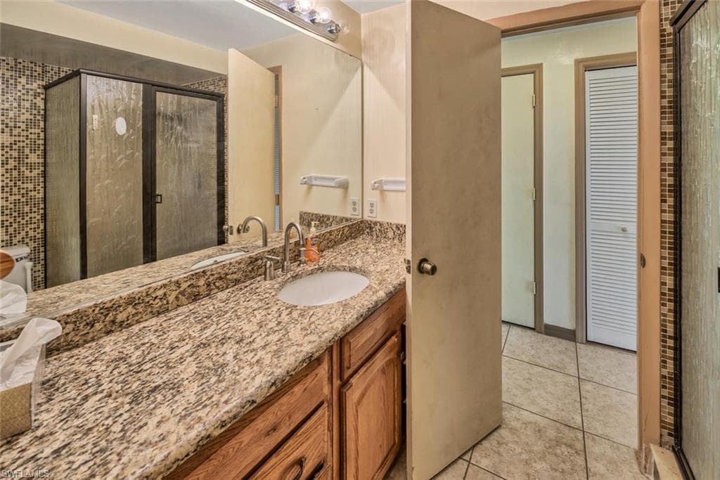 Bathroom with tile patterned flooring, vanity, and an enclosed shower