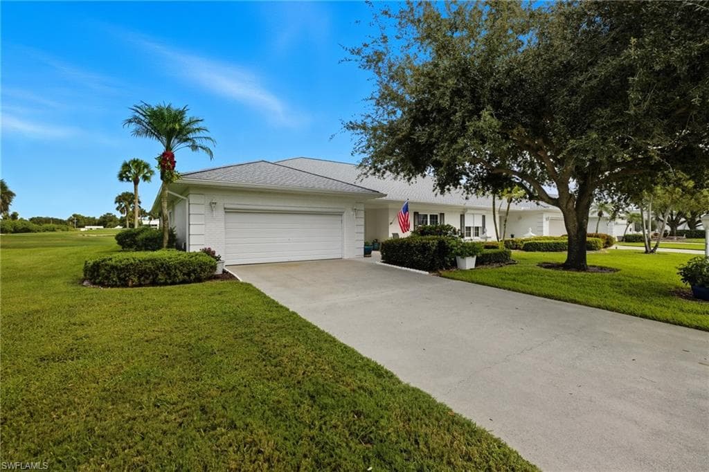Single-story residence featuring a white stucco exterior, an attached two-car garage, mature landscaping, a concrete driveway, and a white shingled roof