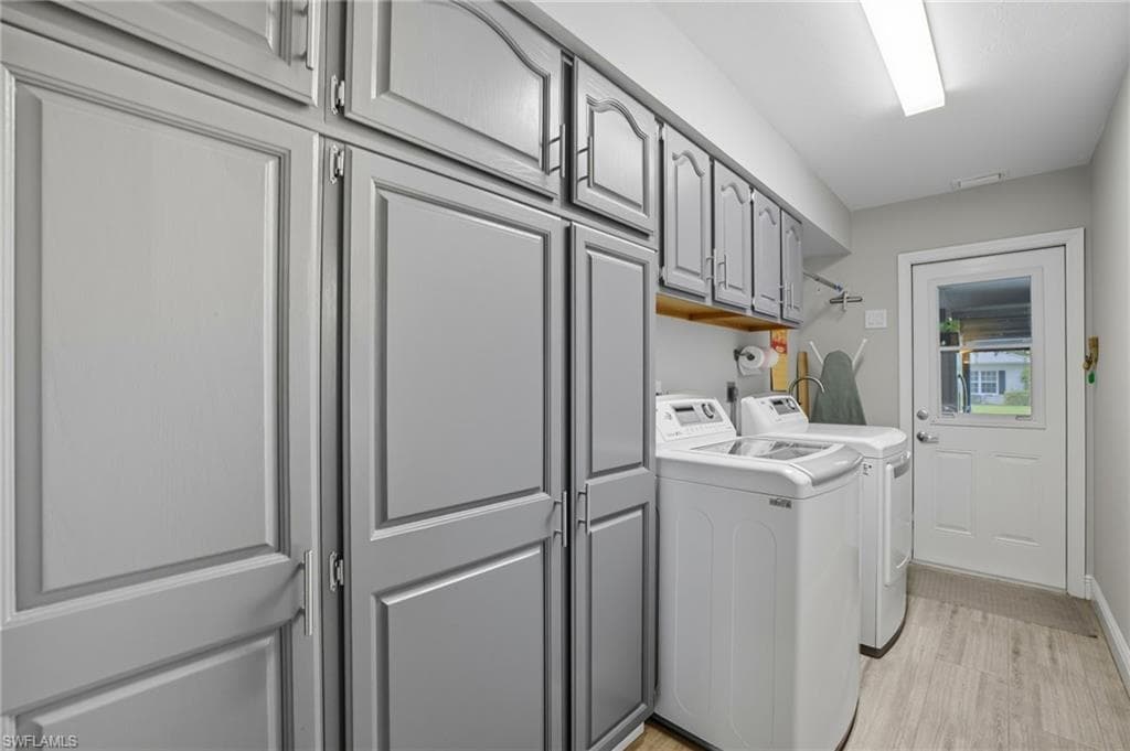 Utility room featuring extensive gray paneled cabinetry providing ample storage, wood-finish flooring, and a white exterior door with clear glass paneling