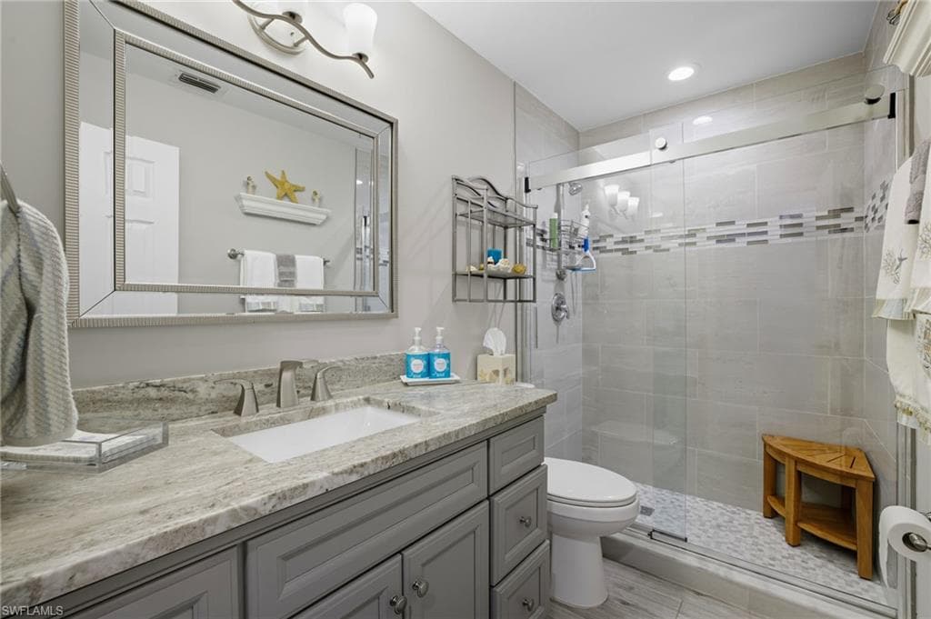 Bathroom featuring a gray vanity with an undermount sink, a light-toned patterned countertop, and a large framed mirror