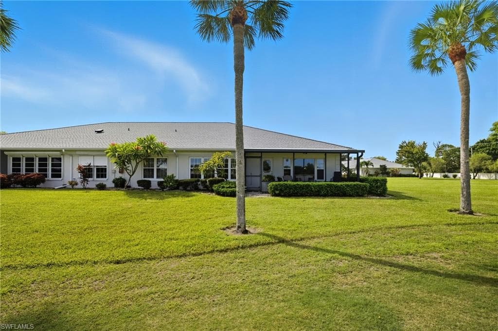 Expansive green lawn bordering a single-story residence with a gray shingle roof