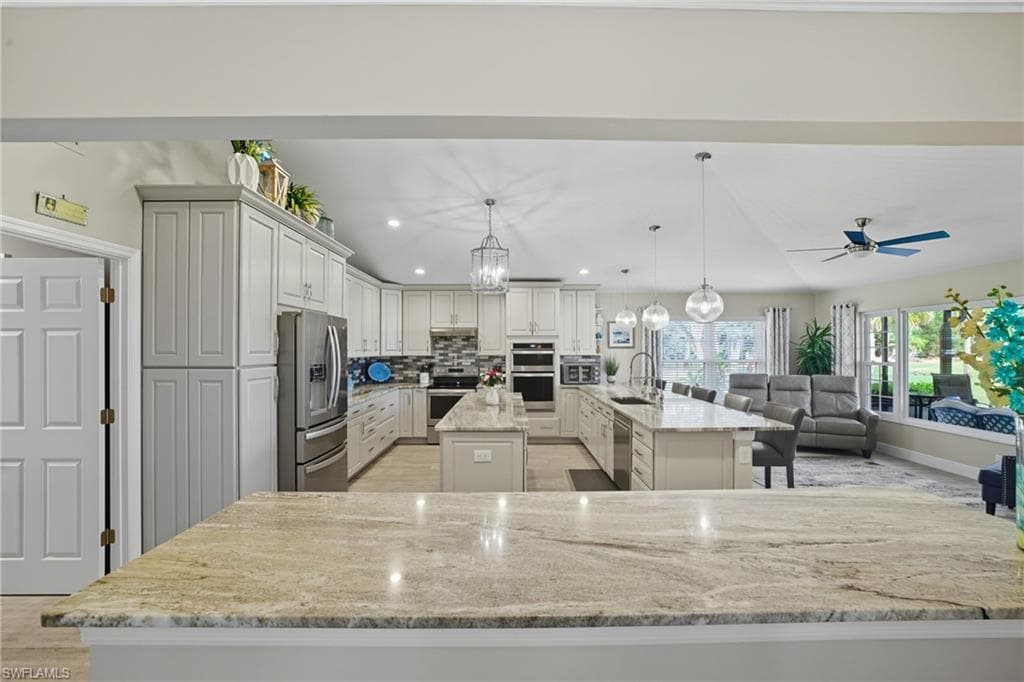 Spacious kitchen featuring a large island with seating, integrated sink, and pendant lighting