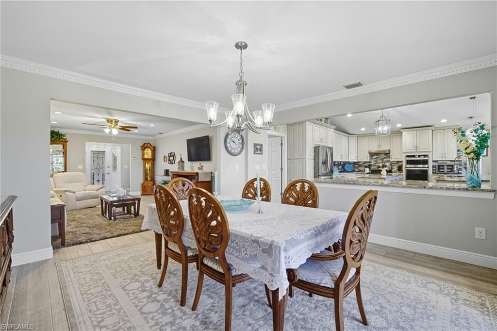 Dining area featuring a chandelier, wood-finish flooring, and crown molding